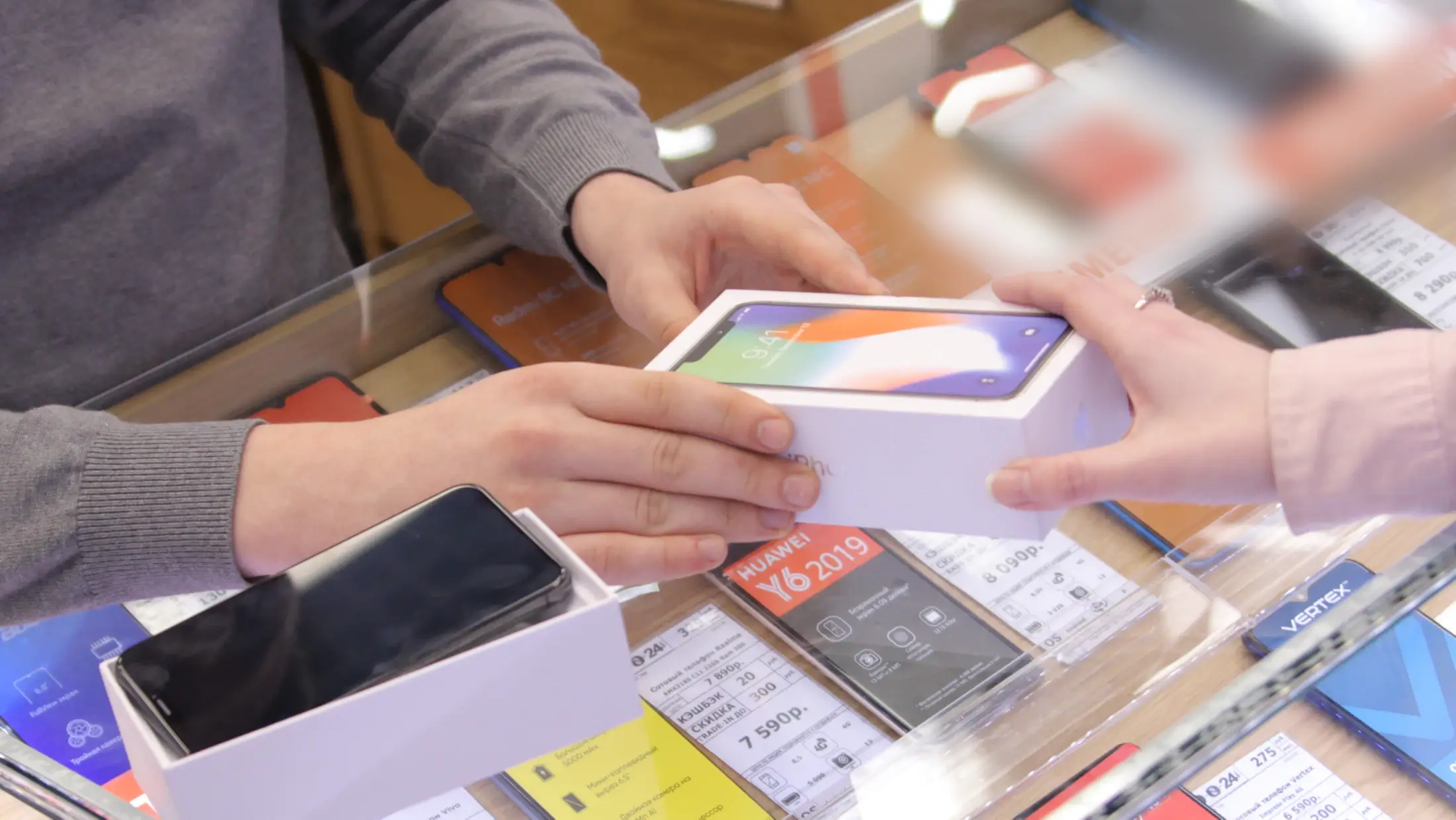 Mağazada satıcı yeni telefonu kutusuyla müşteriye uzatıyor